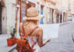 girl looking at a map standing in the middle of a brick street in Europe