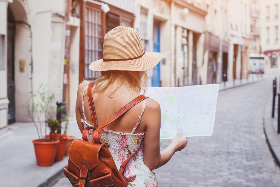 girl looking at a map standing in the middle of a brick street in Europe
