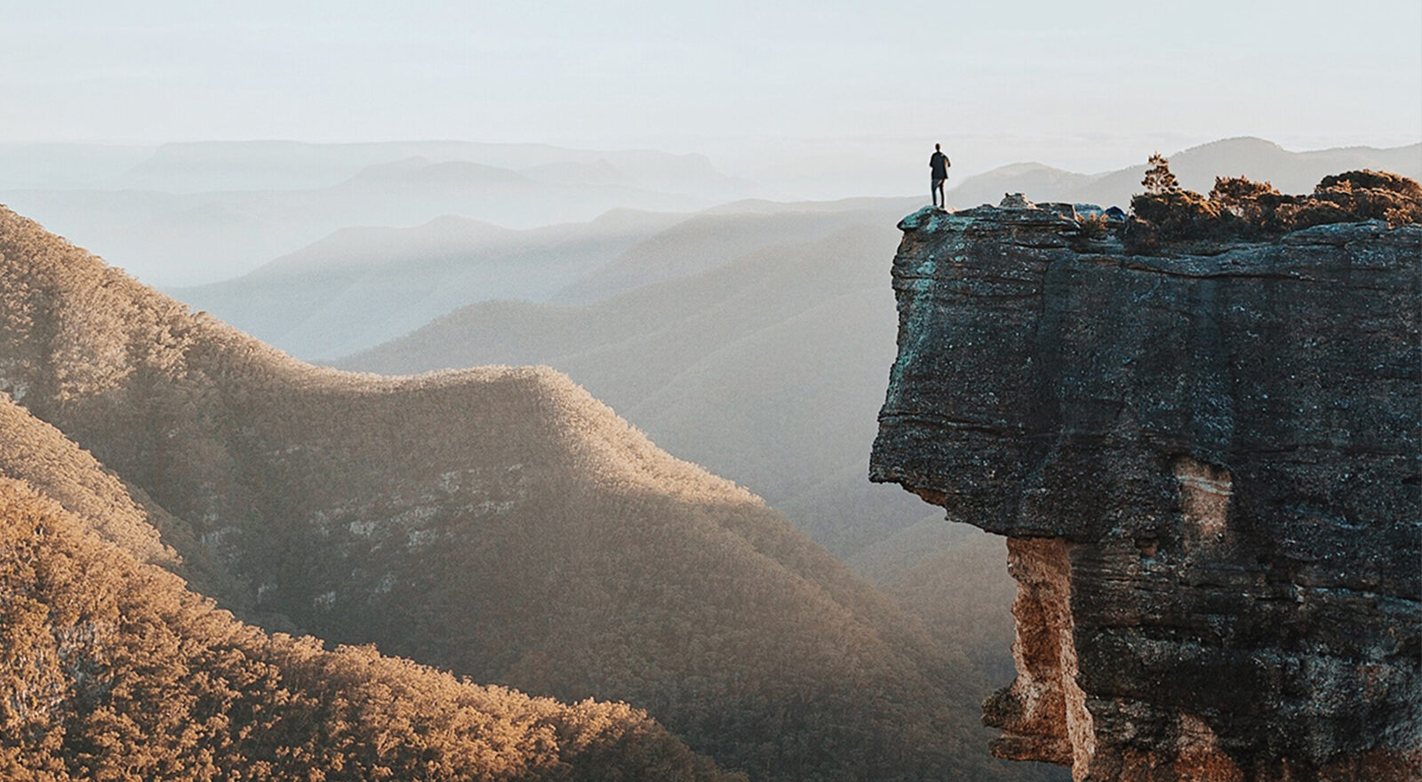 man standing at edge of cliff
