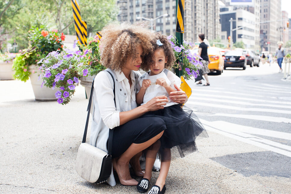mother and daughter standing next to street