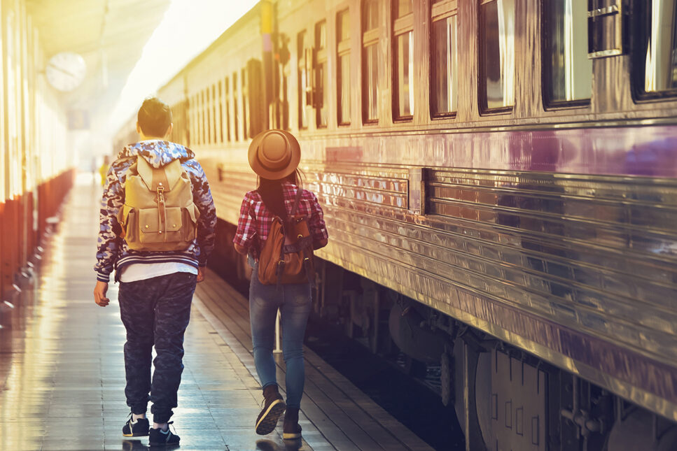 two travelers walking next to a train