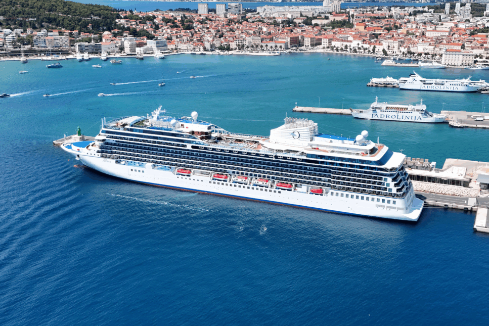 Large white luxury cruise ship docked at the port of Split, Croatia, with turquoise Adriatic waters, Jadrolinija ferries, and the historic old town with red rooftops in the background.